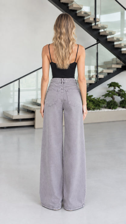 Back view of model showcasing rear pockets and fit of grey wide leg jeans