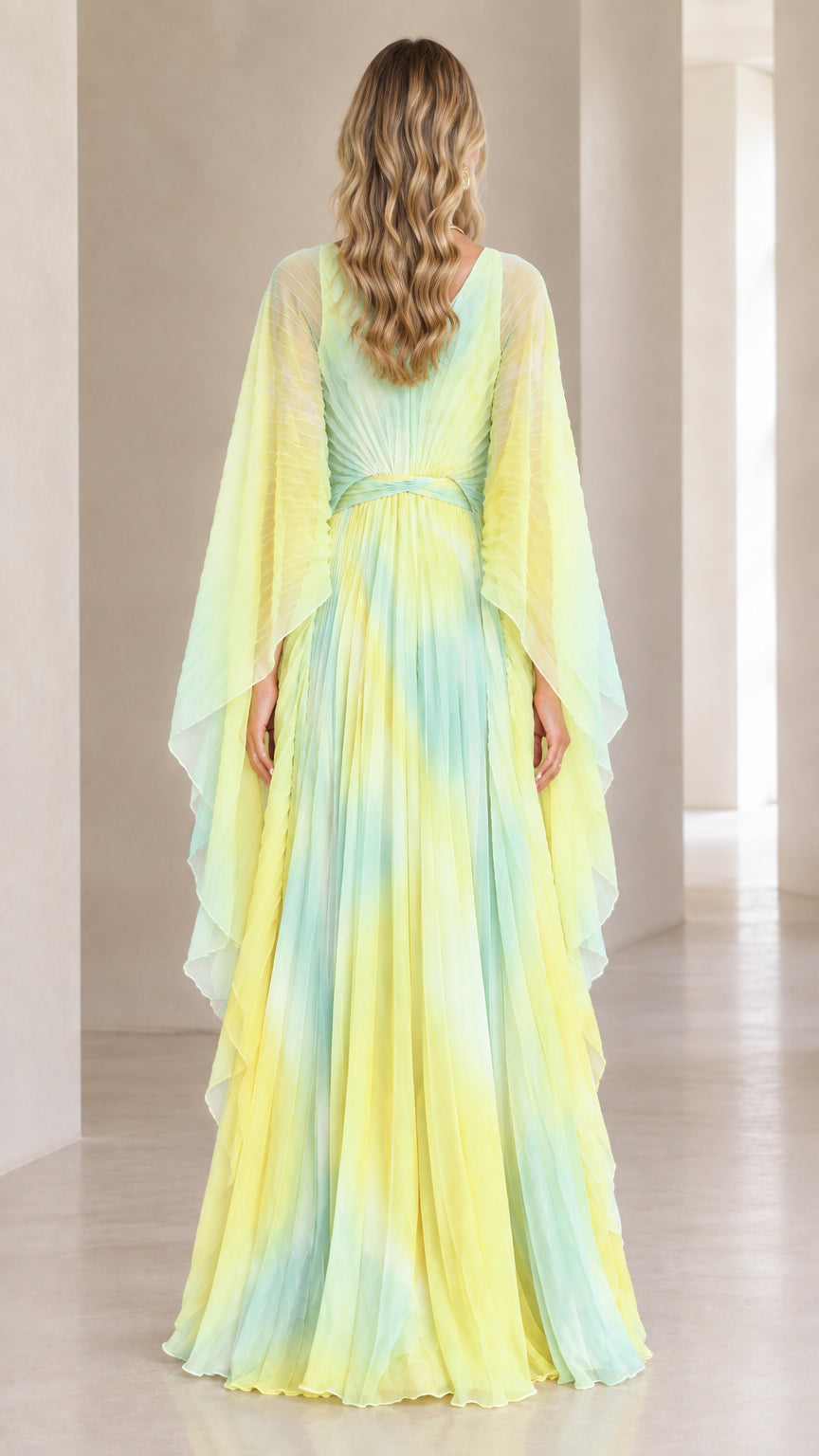 Back view of yellow ombre pleated evening gown showing V-back and cape drape