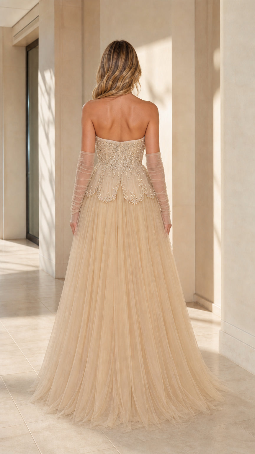Back view of model showing the back cut and flowing champagne tulle skirt