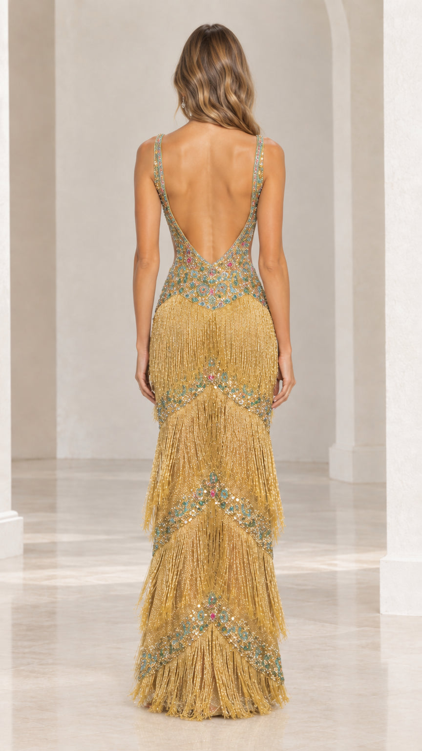 Back view of model wearing gold fringe gown featuring deep low back design