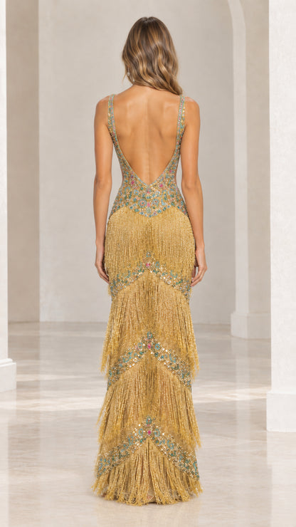 Back view of model wearing gold fringe gown featuring deep low back design