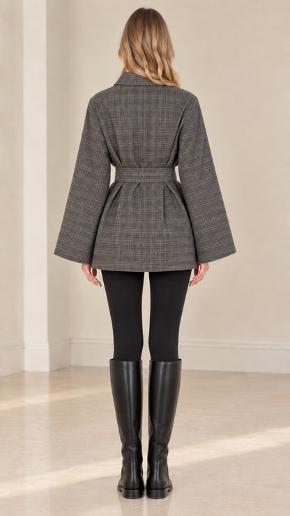Back view of woman wearing grey plaid belted jacket showing back pleat and silhouette