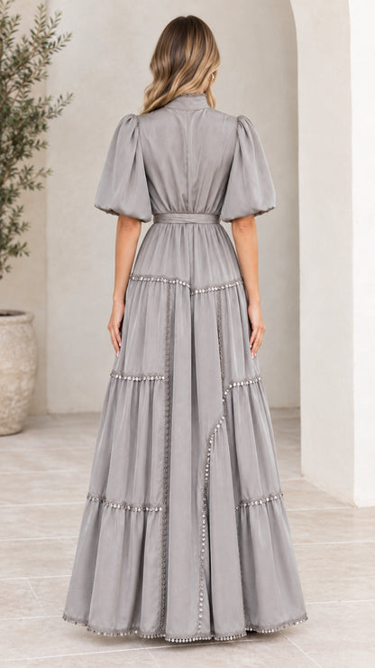 Back view of woman wearing elegant grey tiered maxi dress with belted waist