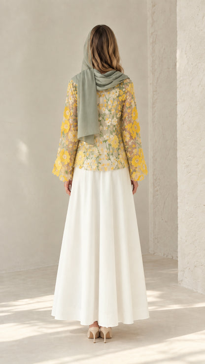 Back view of model wearing flowing white maxi dress with sheer floral lace jacket