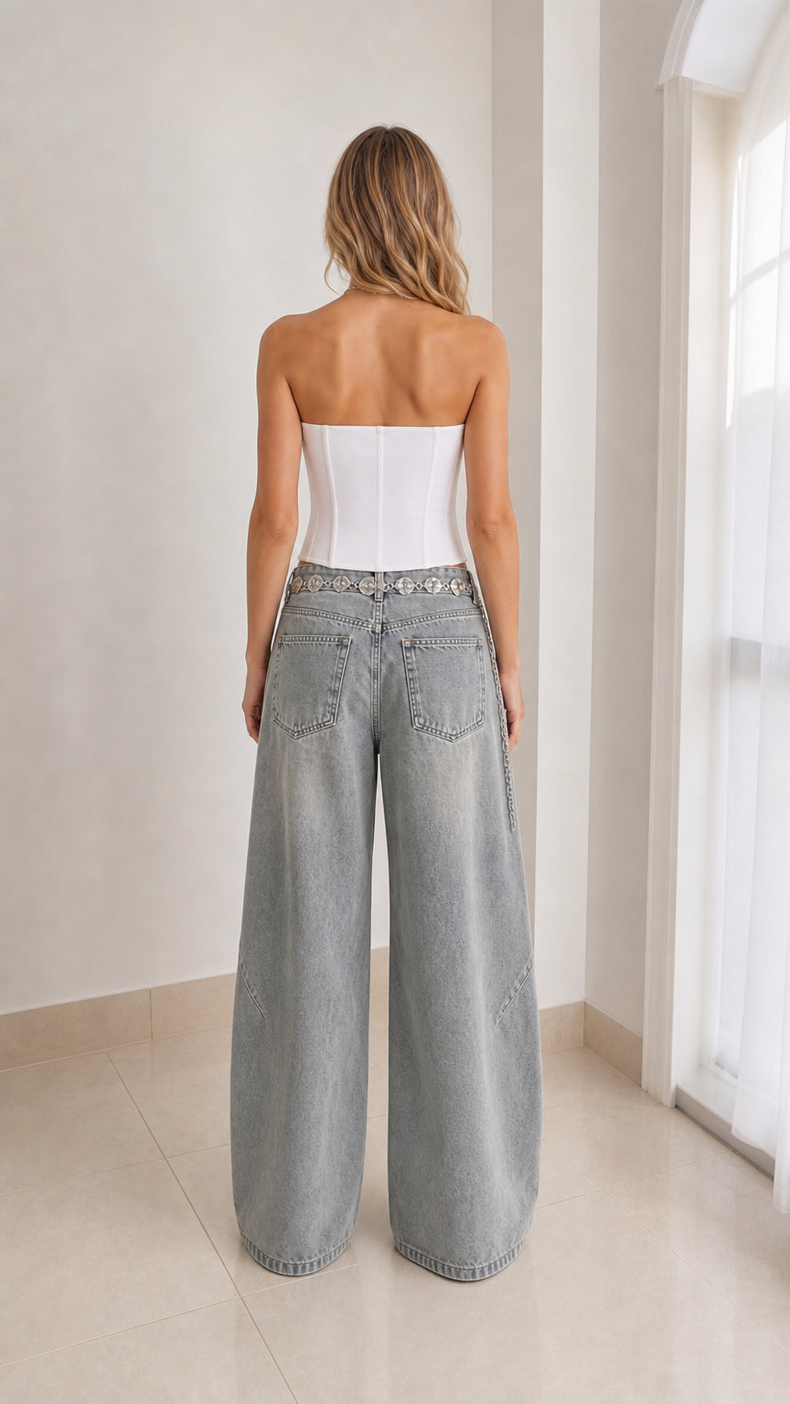 Back view of model wearing washed grey wide-leg jeans showcasing rear pocket placement