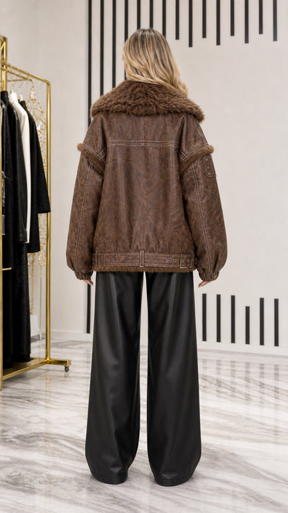 Back view of model showing dropped shoulder seams and belted hem on brown aviator jacket