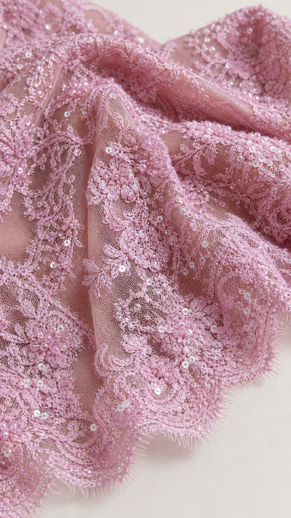 Close-up of pink textured floral lace fabric with subtle embellishments