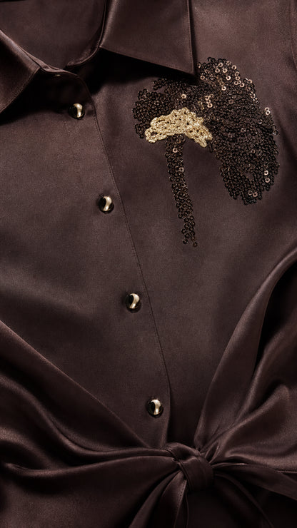 Close-up of dark brown satin blouse collar, buttons, tie waist, and sequin applique