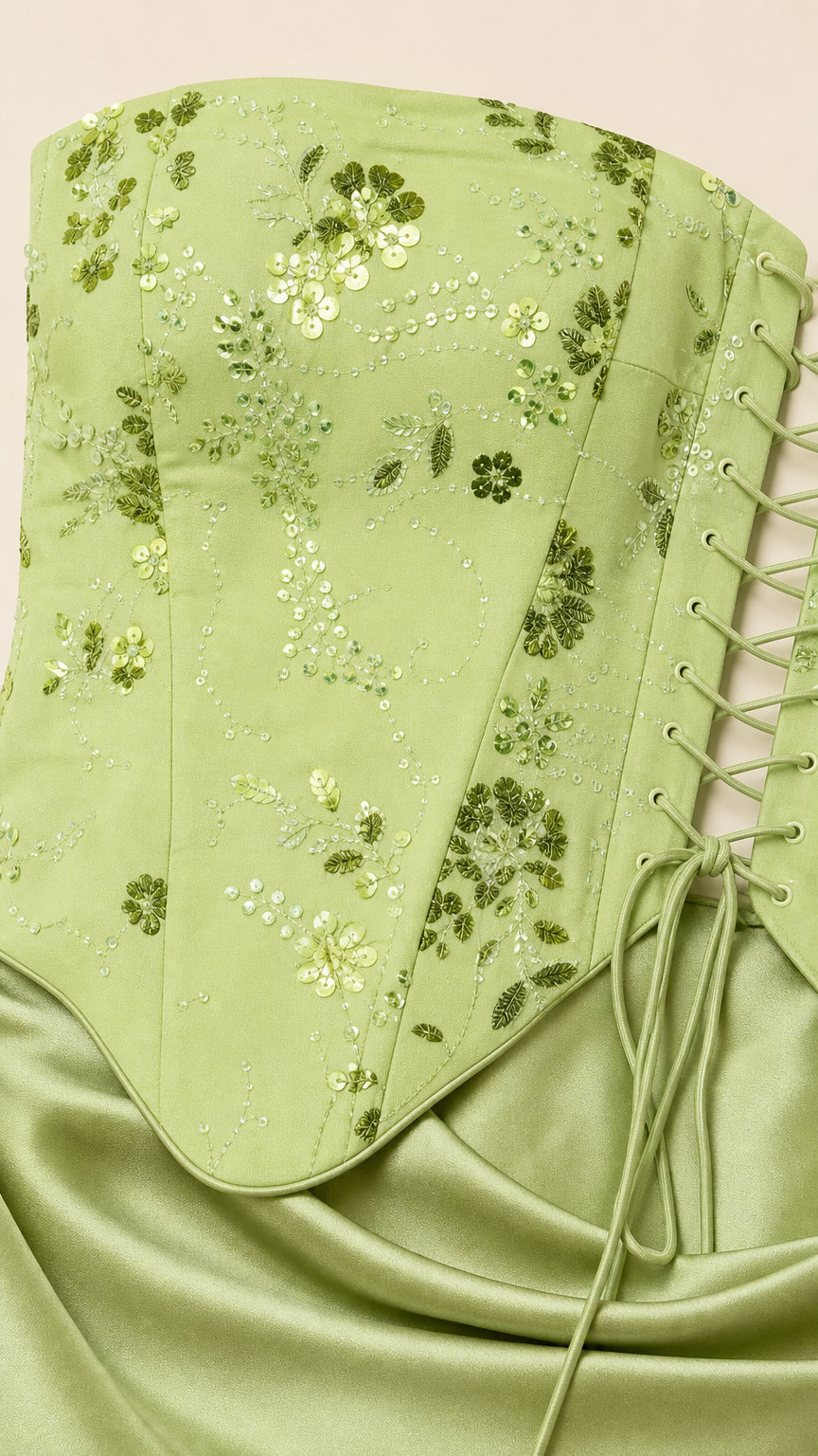 Close-up detail of sage green floral sequin embroidery and lace-up corset side