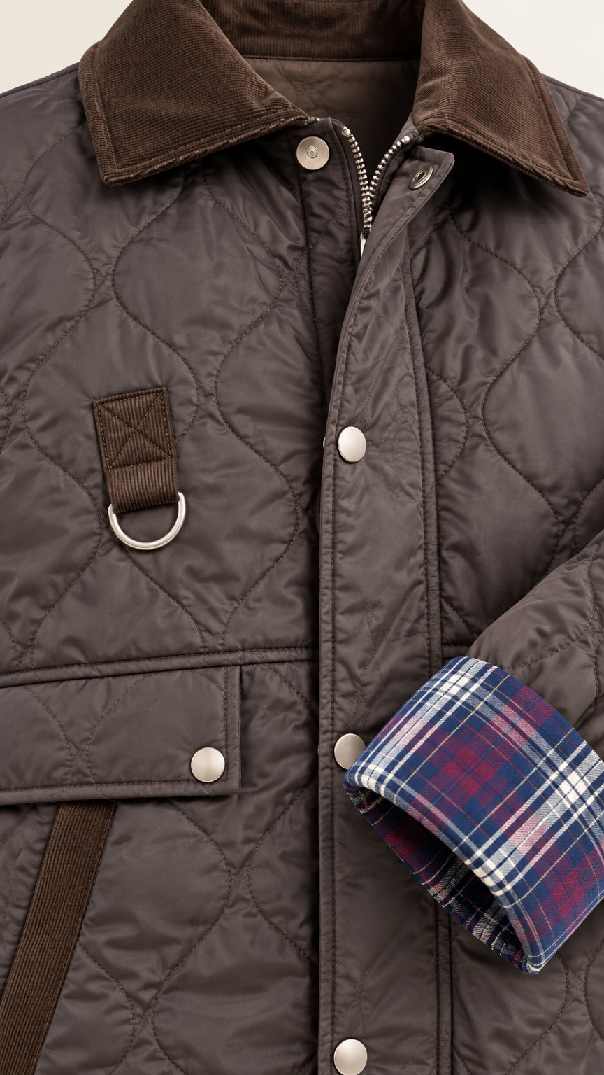 Detailed close-up of dark brown quilted jacket showing corduroy collar, snap buttons, and plaid cuff lining