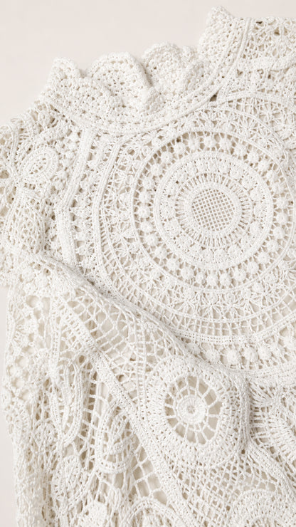 Close-up detail of white geometric crochet lace fabric and mock neck