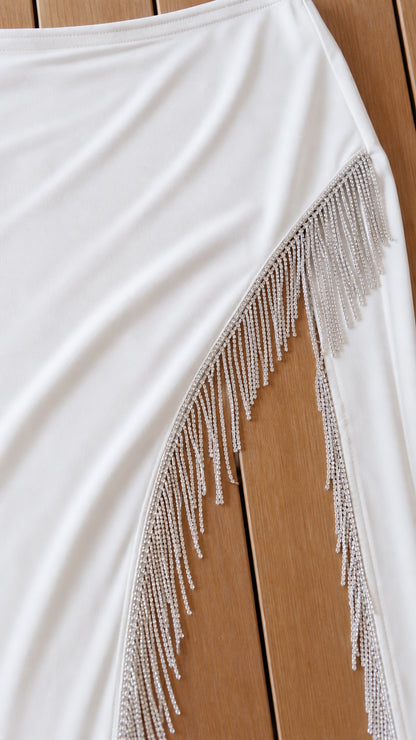 Close up of white maxi skirt side slit featuring sparkling fringe trim