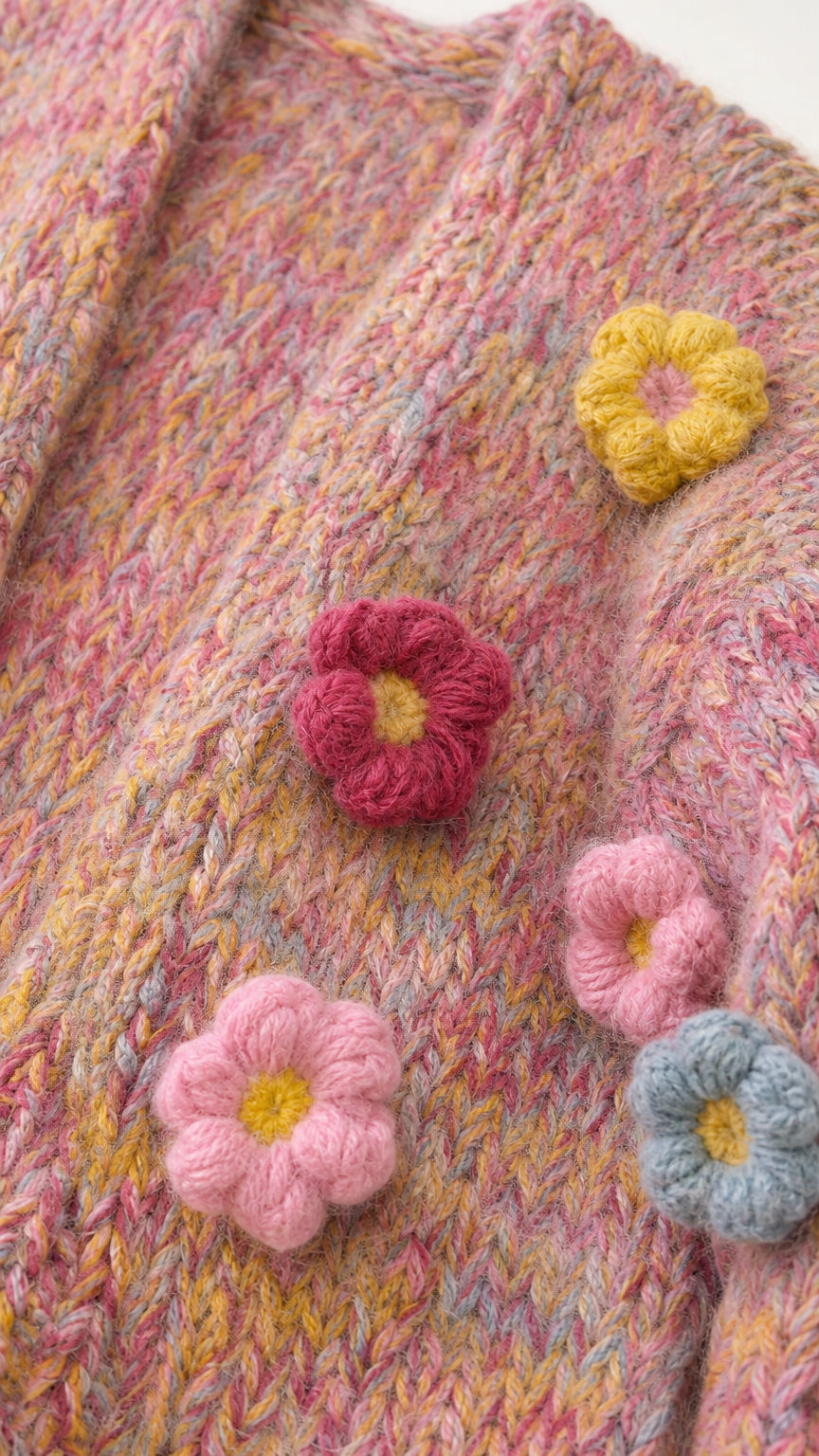 Close-up detail of 3D crochet floral appliques on pink knit fabric