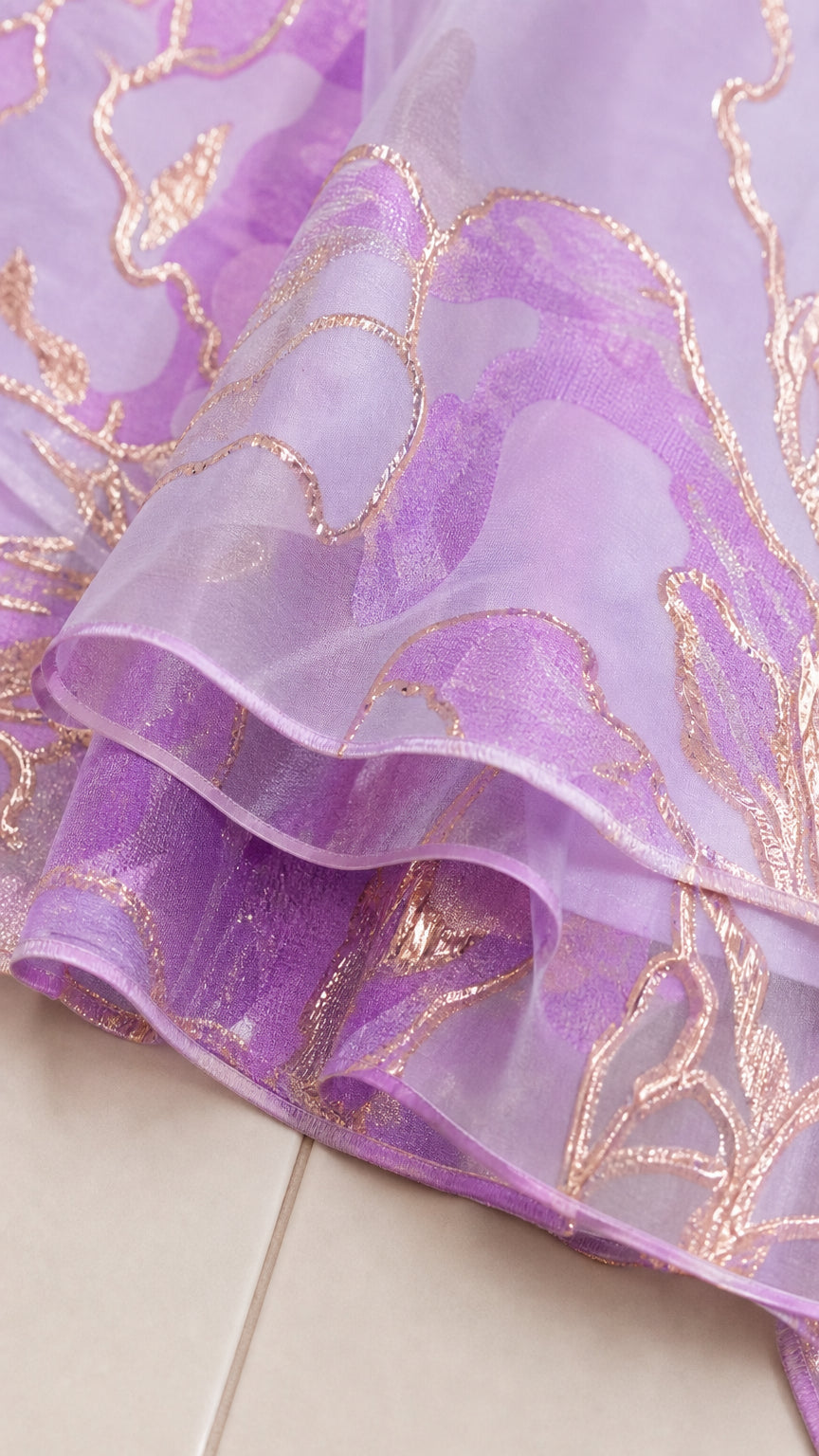 Close-up detail of sheer lavender organza fabric with gold metallic floral embroidery
