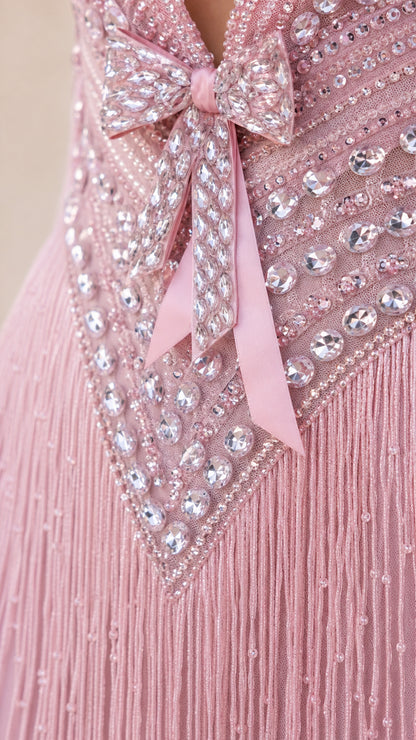 Close-up detail of rhinestone bow embellishments and layered fringe bodice