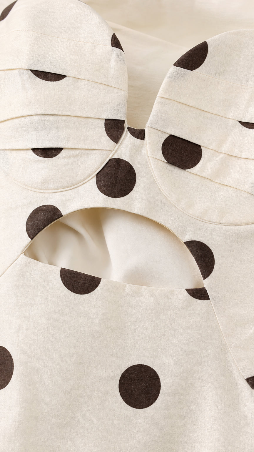 Close-up detail of structured sweetheart bodice and cutout on cream polka dot dress