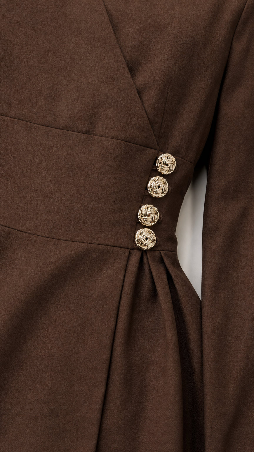 Close-up detail of ornate gold buttons and pleats on brown wrap top