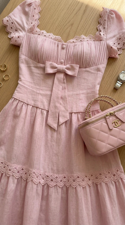 Close-up flat lay of blush pink dress bodice showcasing pleated bust, lace trim, and bow detail
