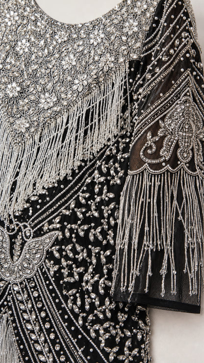 Close-up detail of silver beading, sequins, and hanging fringe on black mesh