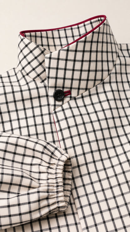 Close-up detail of high collar, contrast trim, and button on plaid blouse