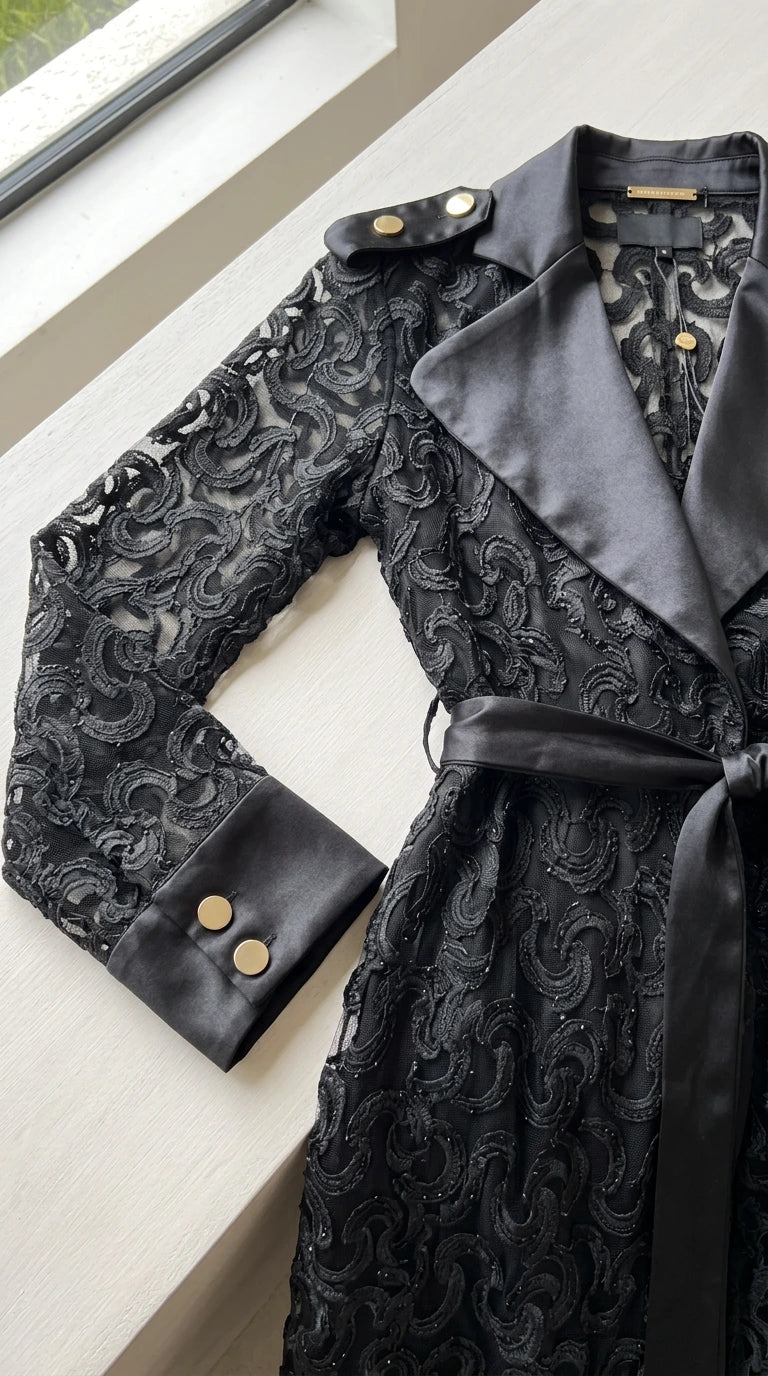 Close-up detail of black lace texture, satin notch collar, and buttoned cuff