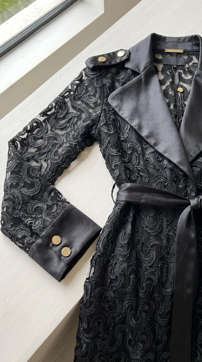 Close-up detail of black lace texture, satin notch collar, and buttoned cuff