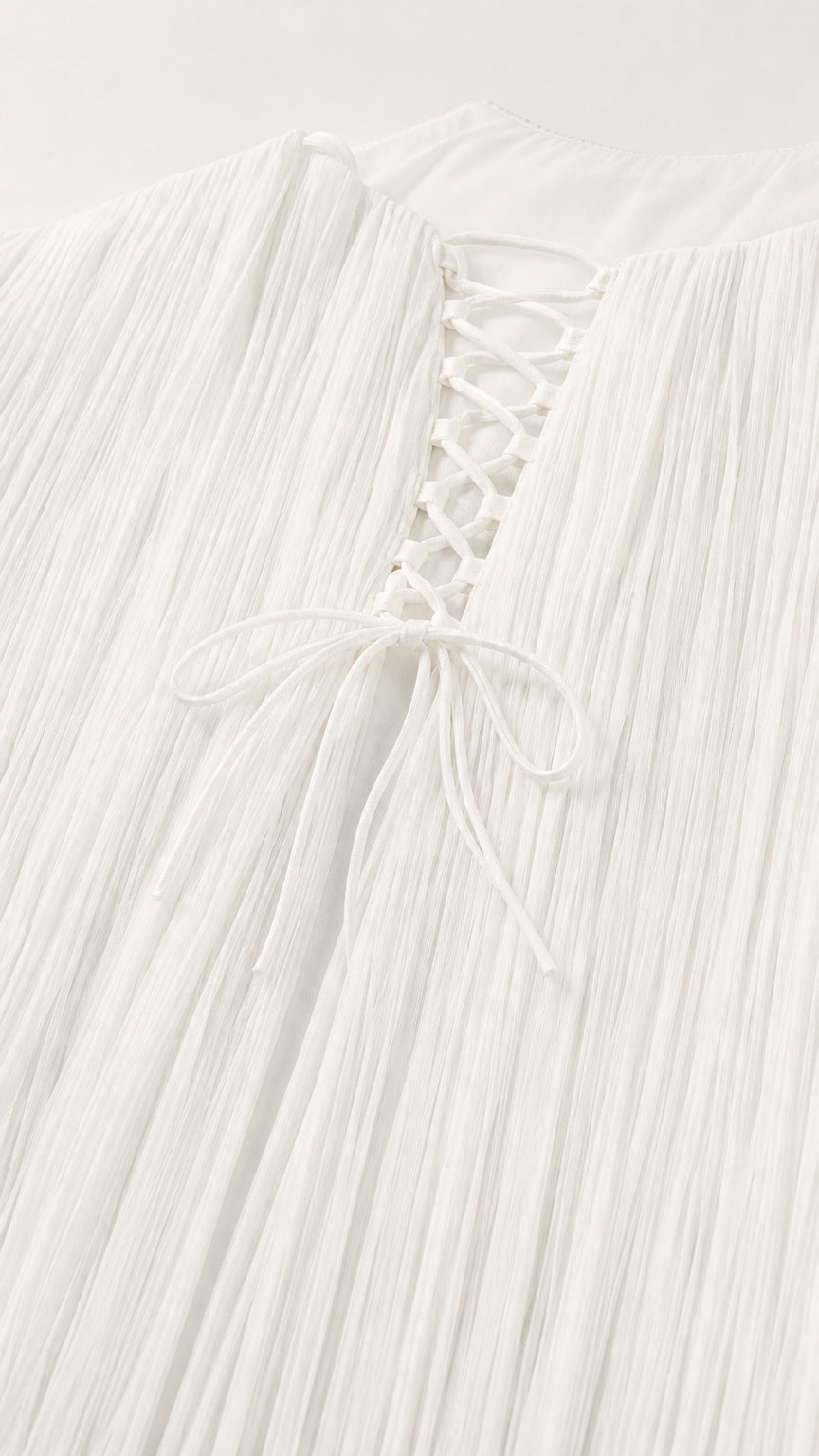 Close-up detail of lace-up back closure and fine pleated fabric texture