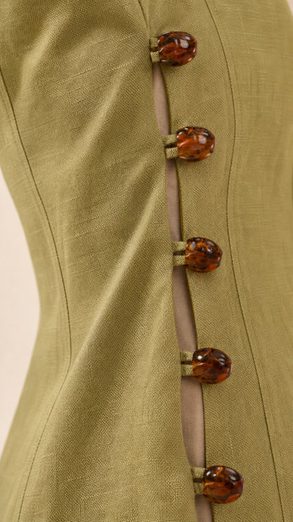 Close-up detail of tortoise-shell buttons on the side of the green dress