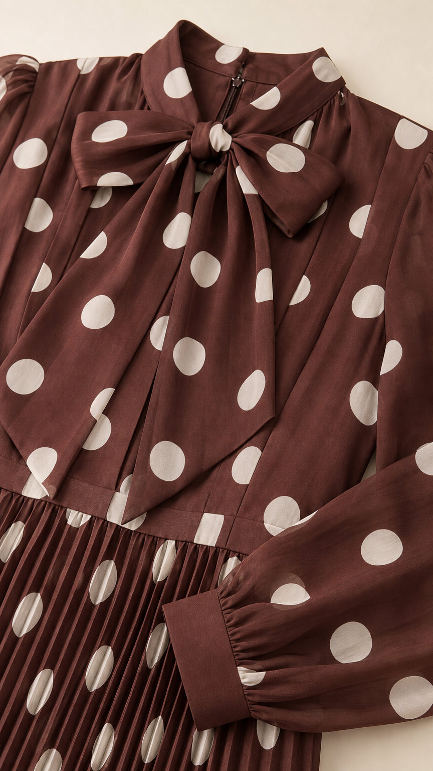 Close-up detail of self-tie bow collar and pleated polka dot fabric on chocolate brown dress