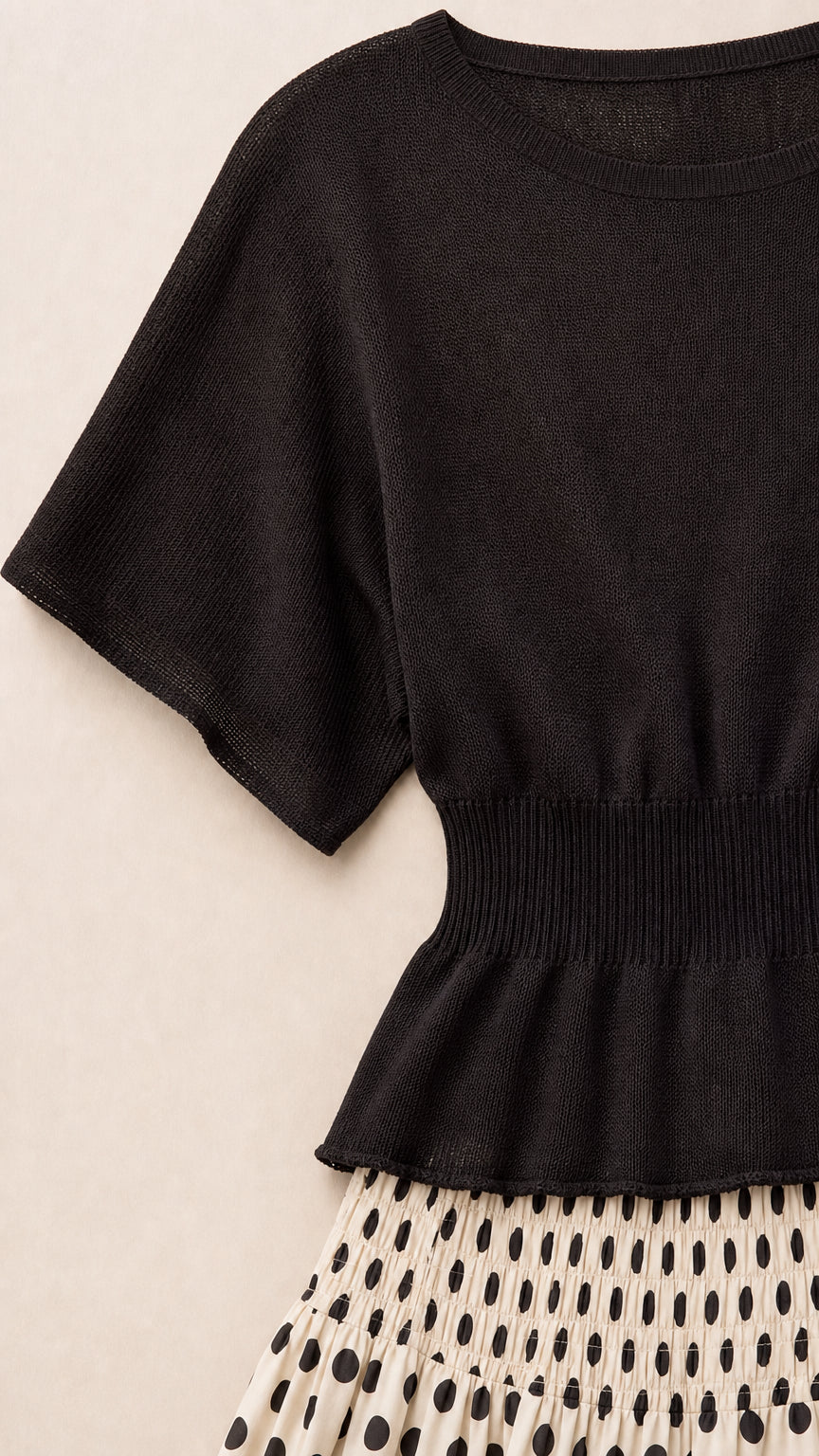 Close-up detail of black knit top with wide ribbed waist and polka dot skirt