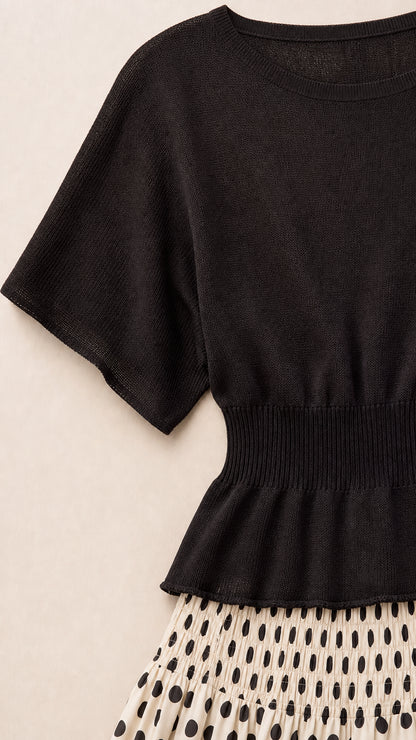 Close-up detail of black knit top with wide ribbed waist and polka dot skirt