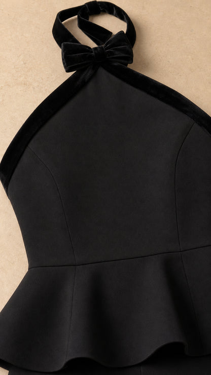 Close-up detail of black halter neckline with velvet bow and peplum waist