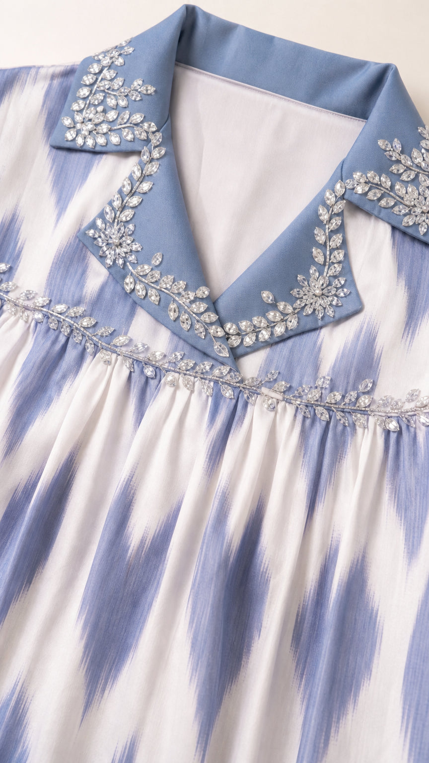 Close-up of crystal-embellished lapel collar and pleated neckline on Light Blue tunic