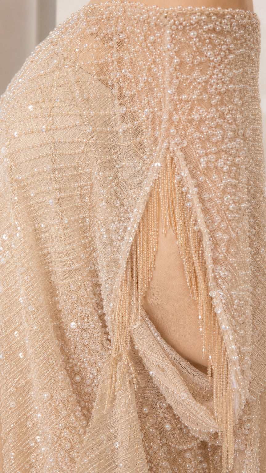 Close-up detail of champagne beaded mesh fabric and sleeve fringe trim