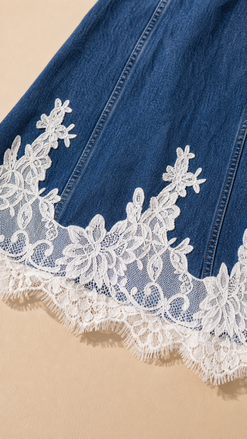 Close-up detail of white scalloped floral lace trim along the denim hemline
