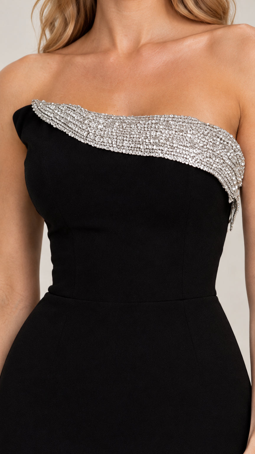 Close-up of sparkling rhinestone trim along the strapless neckline on black dress