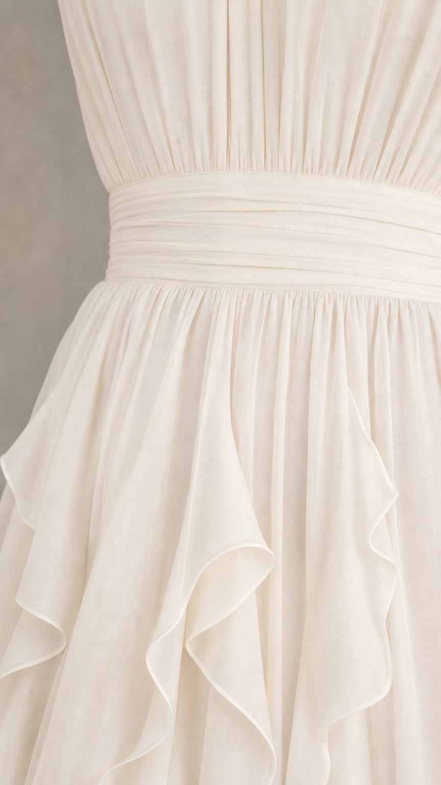 Close-up detail of pleated bodice and cascading ruffle skirt on white maxi dress