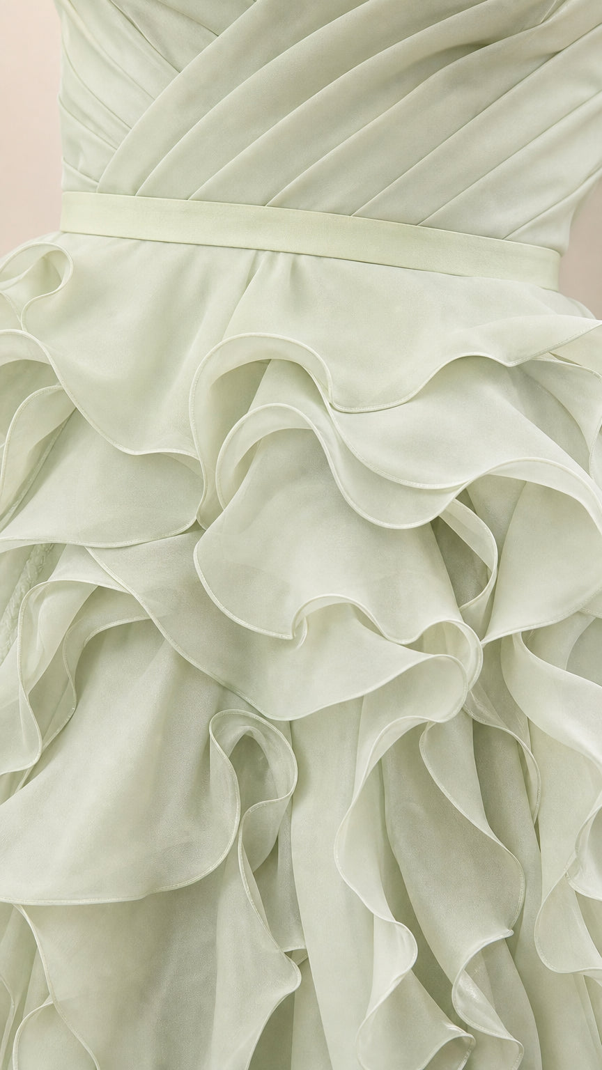 Close-up detail of structured waistband and cascading ruffles on sage green dress