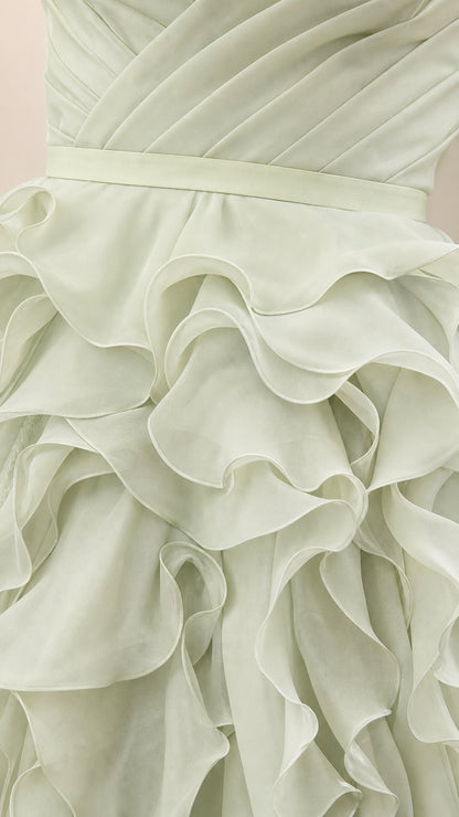 Close-up detail of structured waistband and cascading ruffles on sage green dress