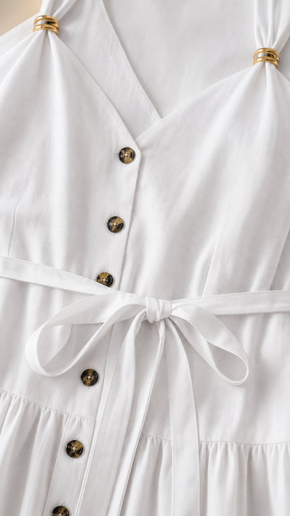 Close-up detail of V-neckline, buttons, and tie belt on white dress