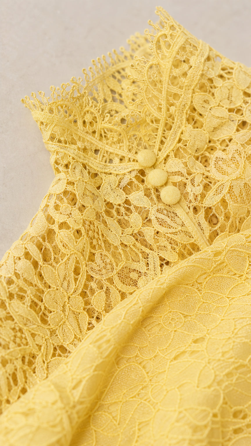 Close-up detail of yellow lace high neckline and covered button accents