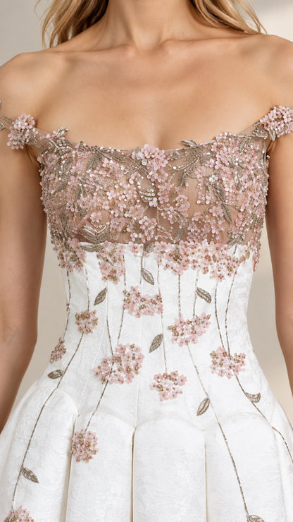 Close-up detail of bodice showing 3D floral applique, sheer mesh neckline, and structured pleating