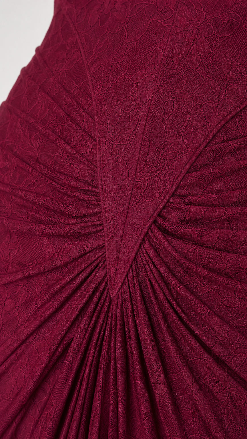 Close-up detail of textured burgundy floral lace and sunburst gathered pleats