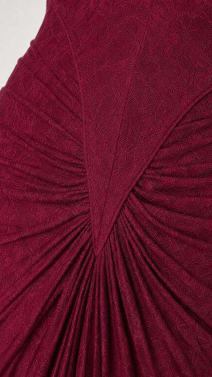 Close-up detail of textured burgundy floral lace and sunburst gathered pleats