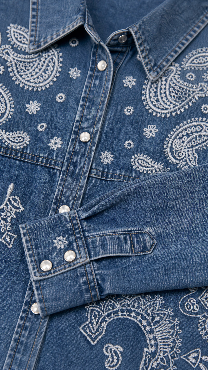 Close-up detail of paisley pattern, point collar, and buttoned cuff on denim shirt