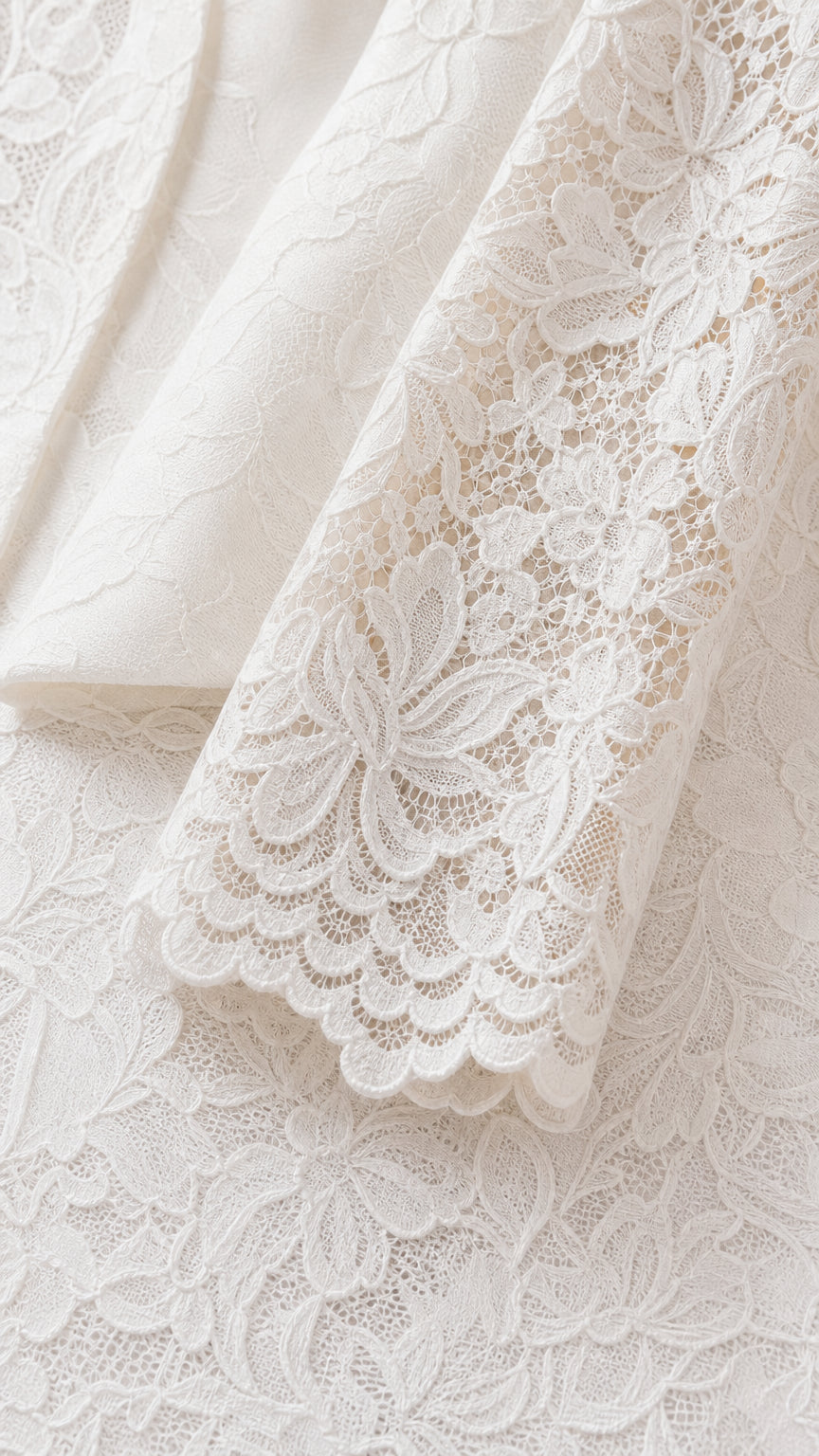 Close-up detail of white scalloped floral lace sleeve cuff and tailored lapel