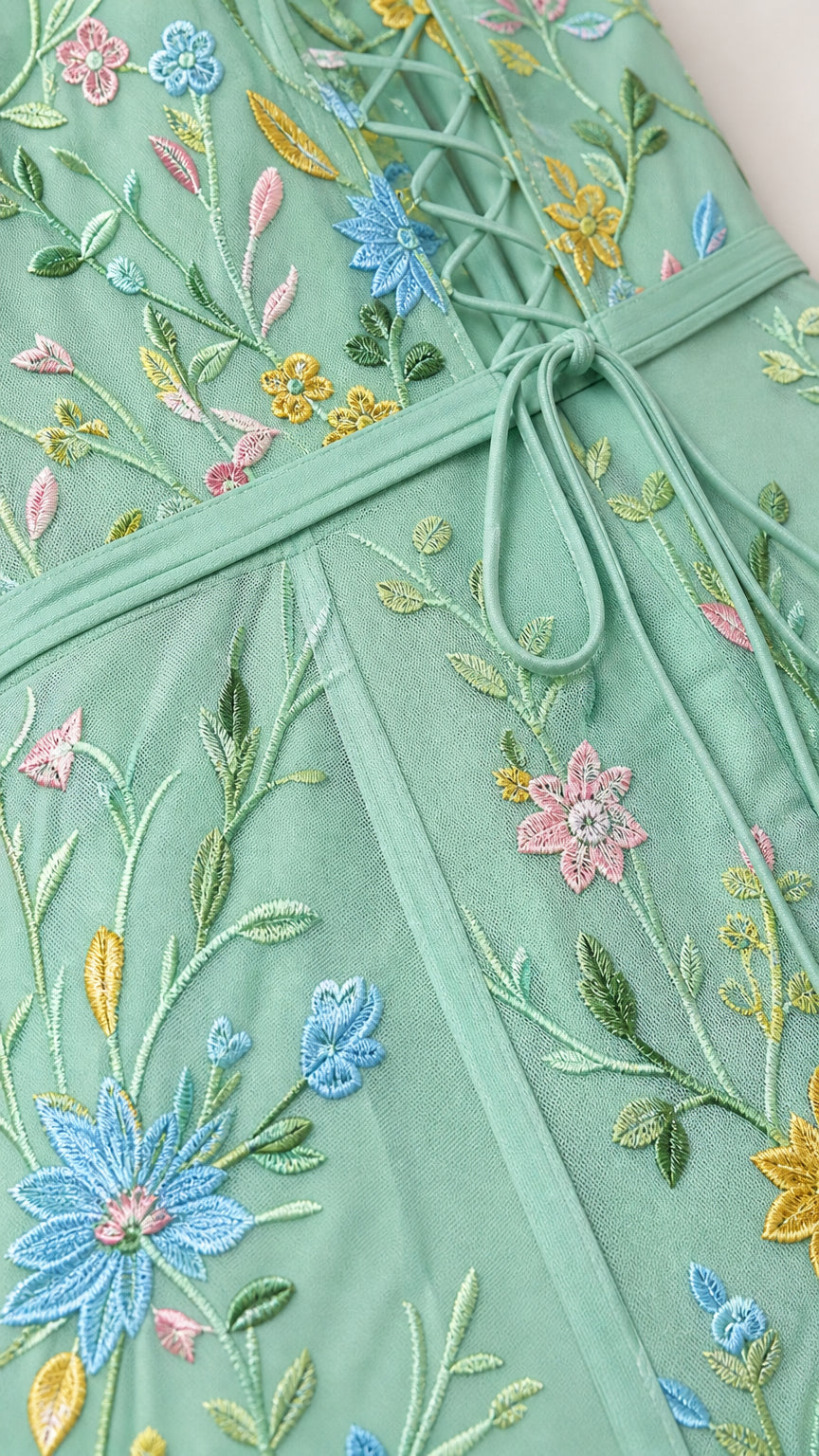 Close-up of floral embroidery and mesh texture on mint green dress