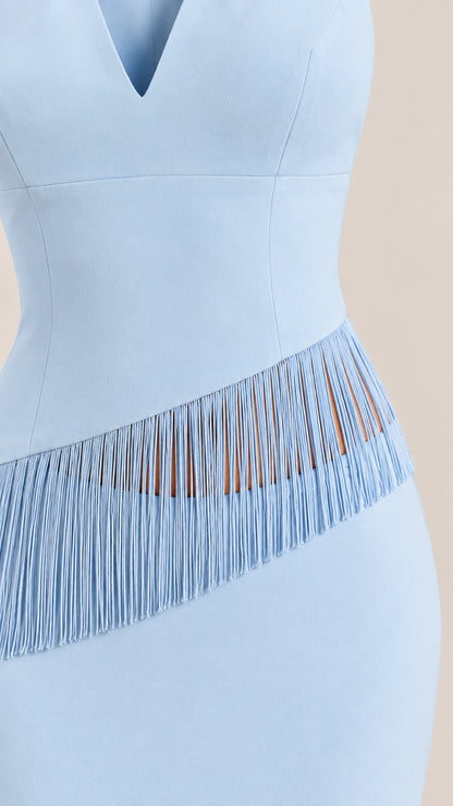 Close-up of waistline showing diagonal fringe trim detail on light blue dress