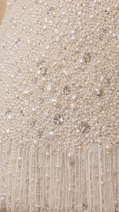 Close-up detail of beads, pearls, and fringe hem