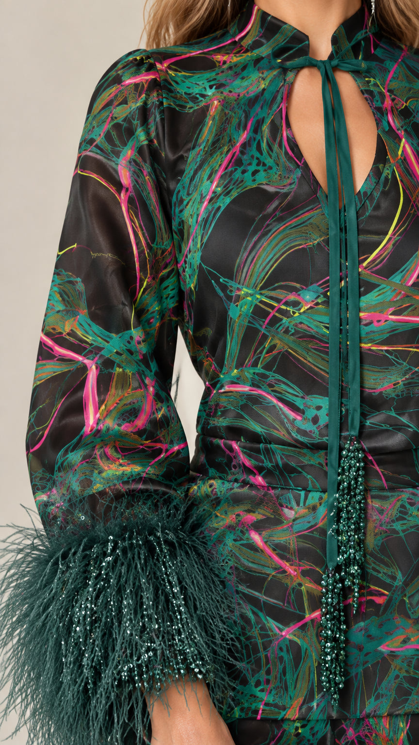 Close-up detail of keyhole tie neckline, beaded cords, and feather cuffs in Emerald Black